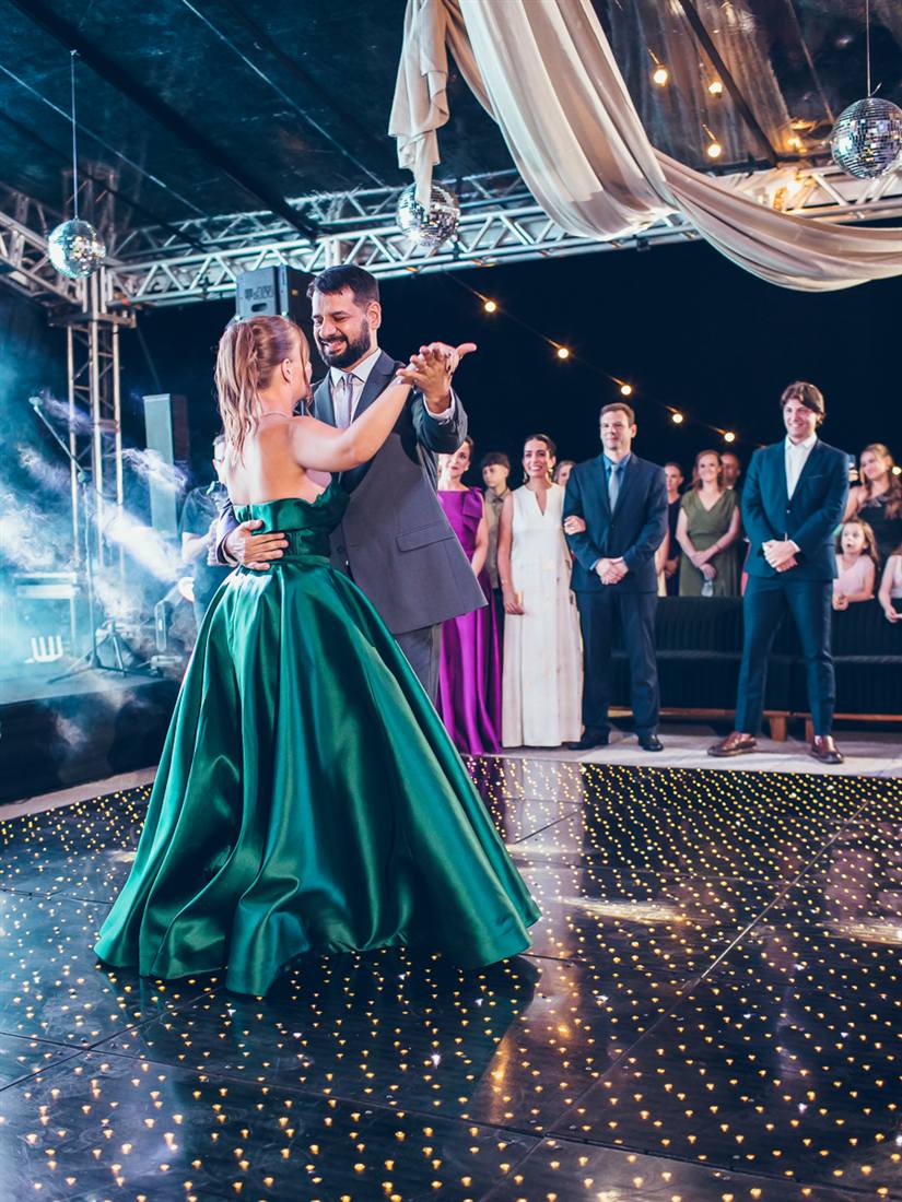 Debutante dançando a valsa com o pai na pista, sob a tenda, com os convidados ao fundo