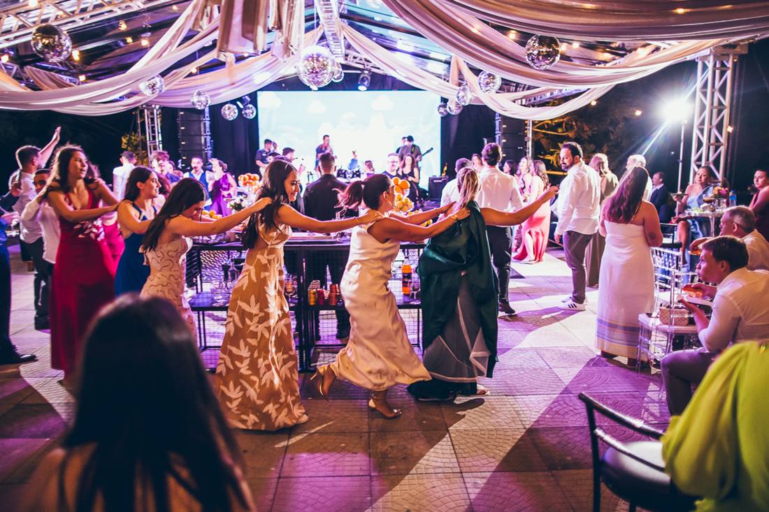 Convidados dançando no salão, com a banda no palco ao fundo