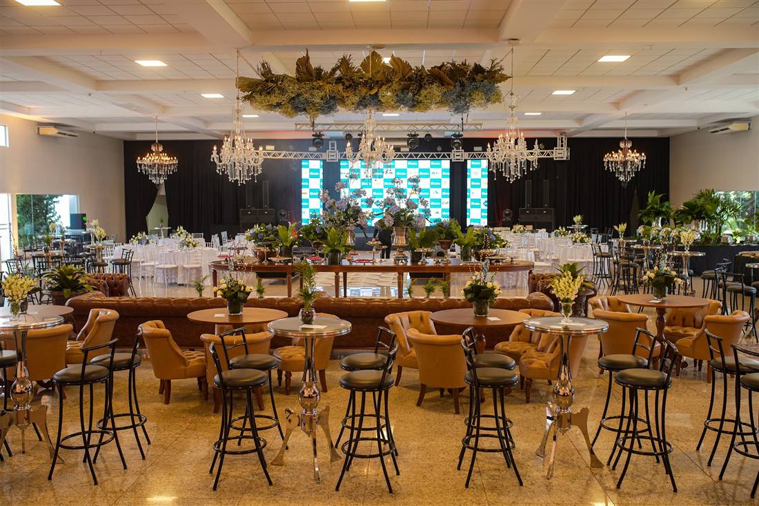 Salão montado para evento de empresa, com lounge, mesas e painéis de LED