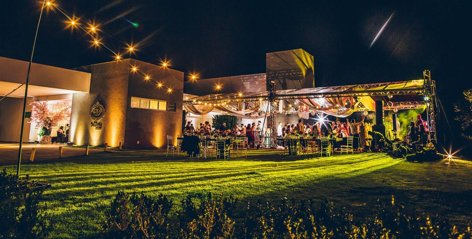 O Gabbana Jardins à noite, com o gramado e a tenda iluminados durante uma festa