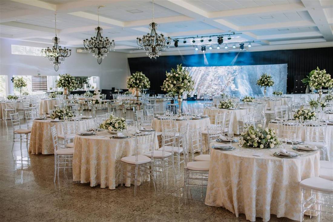 Salão Flor de Lótus montado com mesas redondas e arranjos de flores
