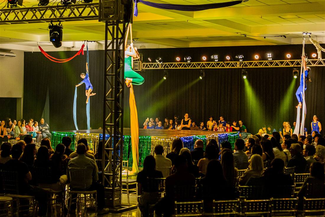 Plateia lotada assistindo a um espetáculo com acrobacia aérea